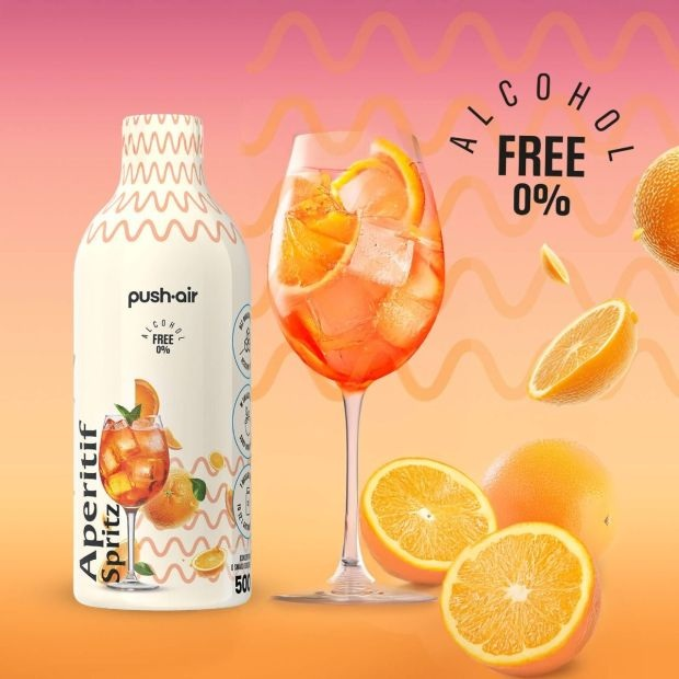 Butelka Aperitif Spritz obok szklanki z lodem, pomarańczą i pryśnięciem.