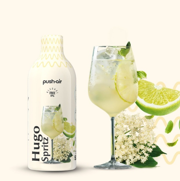 Butelka Hugo Spritz i szklanka z drinkiem, limonką, miętą, kwiatami bzu.