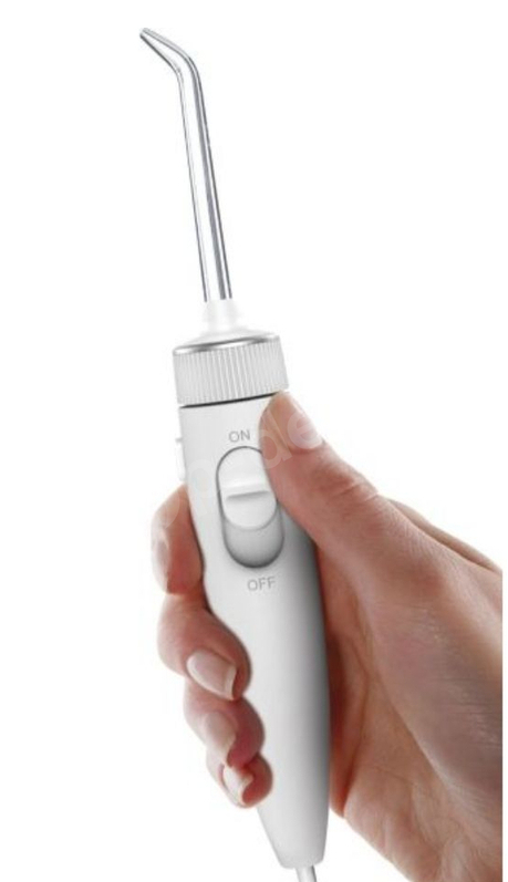 Dłoń trzyma białe urządzenie do płukania jamy ustnej z przezroczystą końcówką.