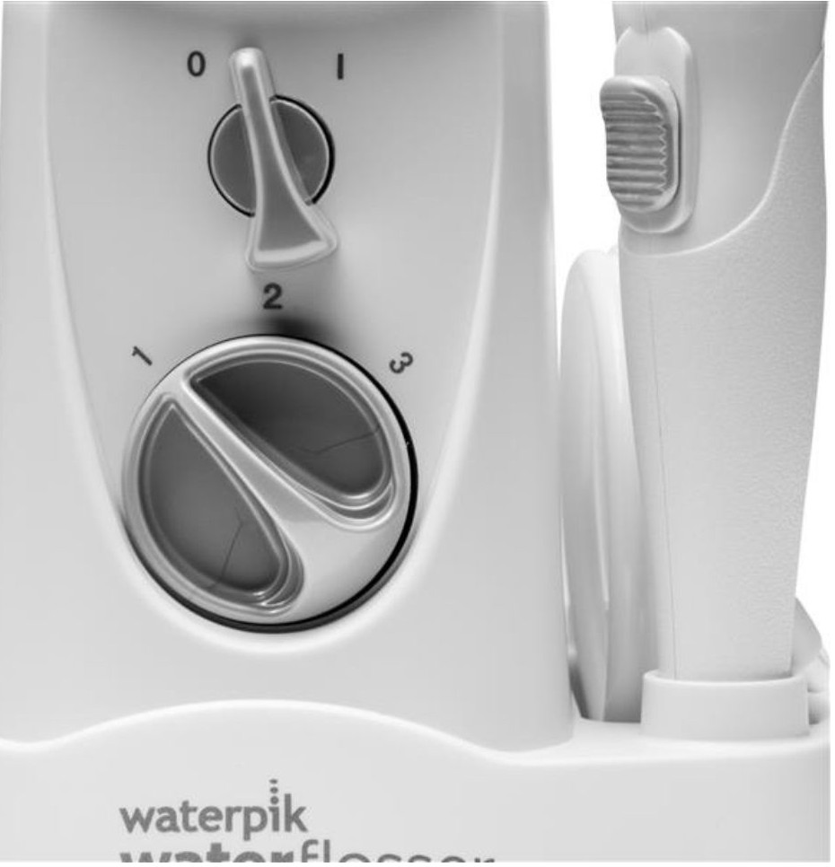 Zbliżenie białego urządzenia Waterpik z pokrętłem i przełącznikiem.