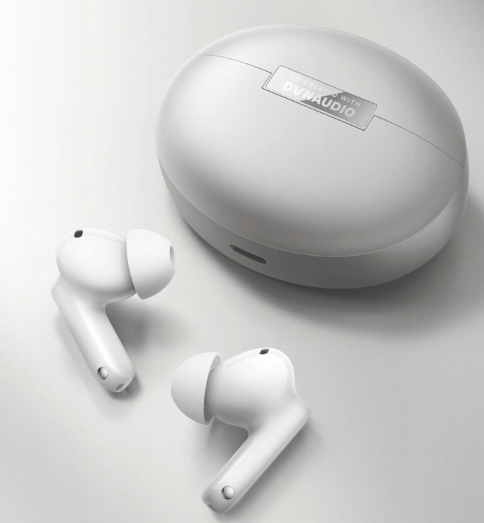 Białe słuchawki bezprzewodowe i etui ładujące z logo Dynaudio.