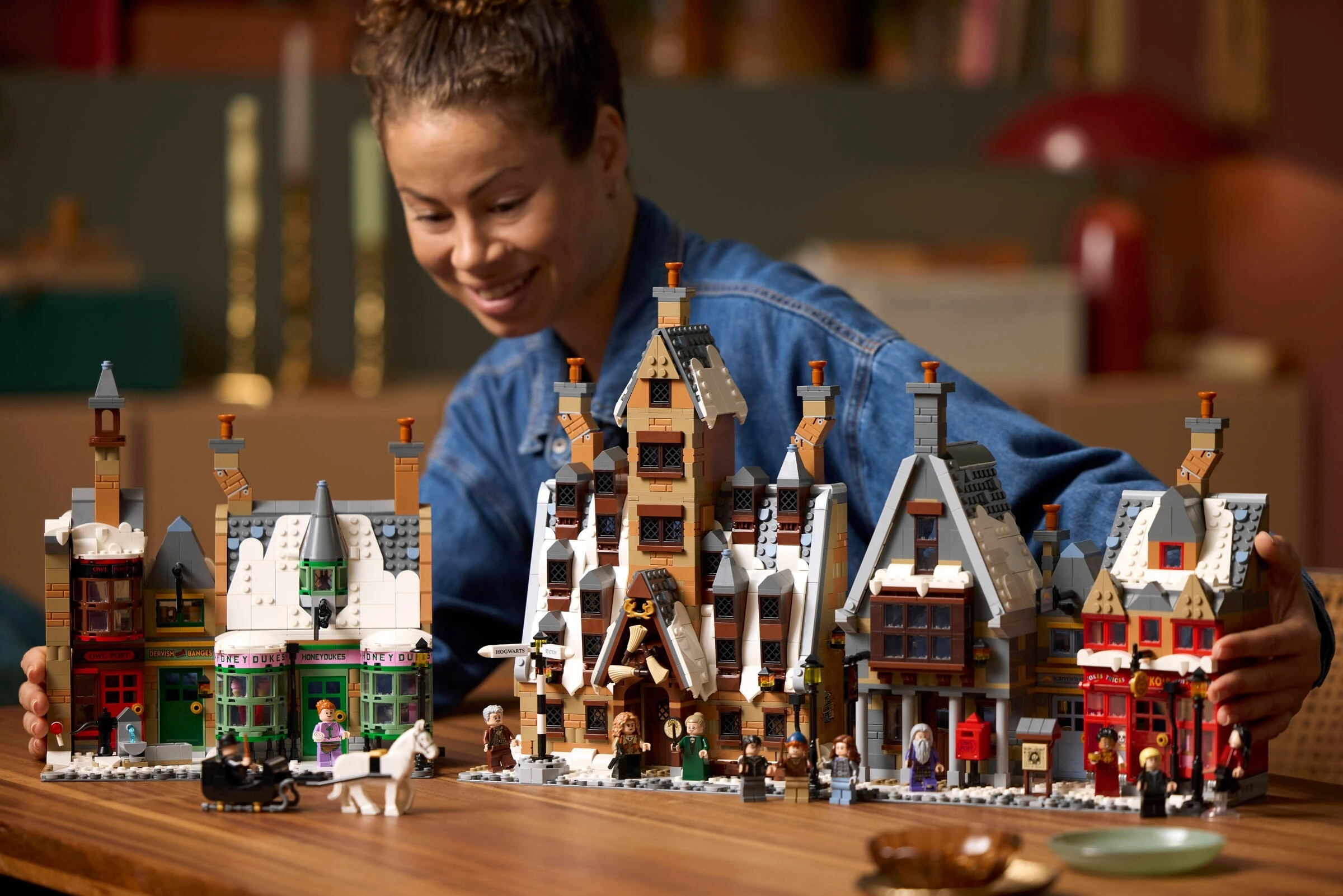 Zestaw Lego przedstawia sceny z Harry'ego Pottera z figurkami, kobieta w tle.