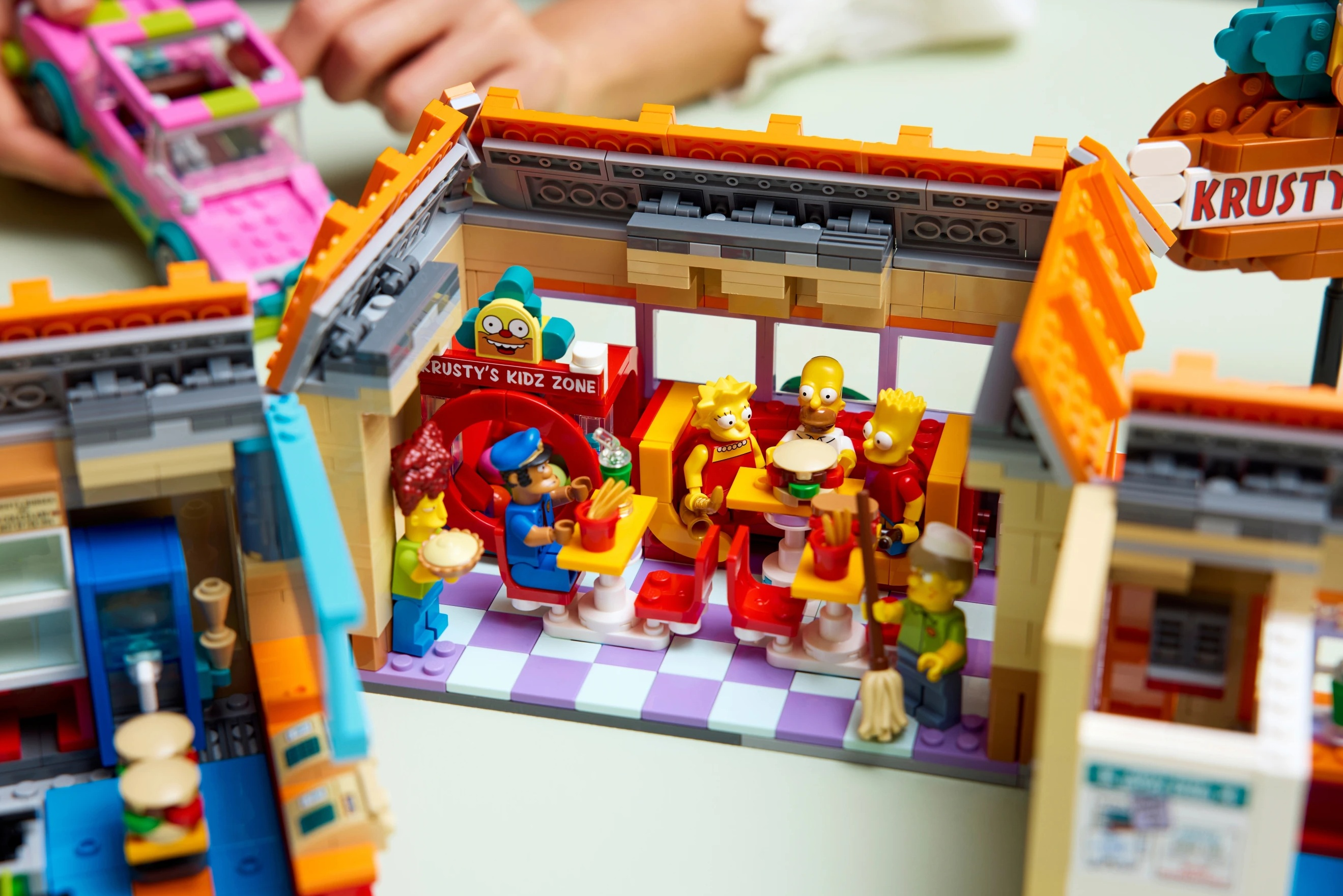 Scena LEGO Simpsonów: Krusty Burger, postacie jak Homer, Bart, Lisa, policjant.