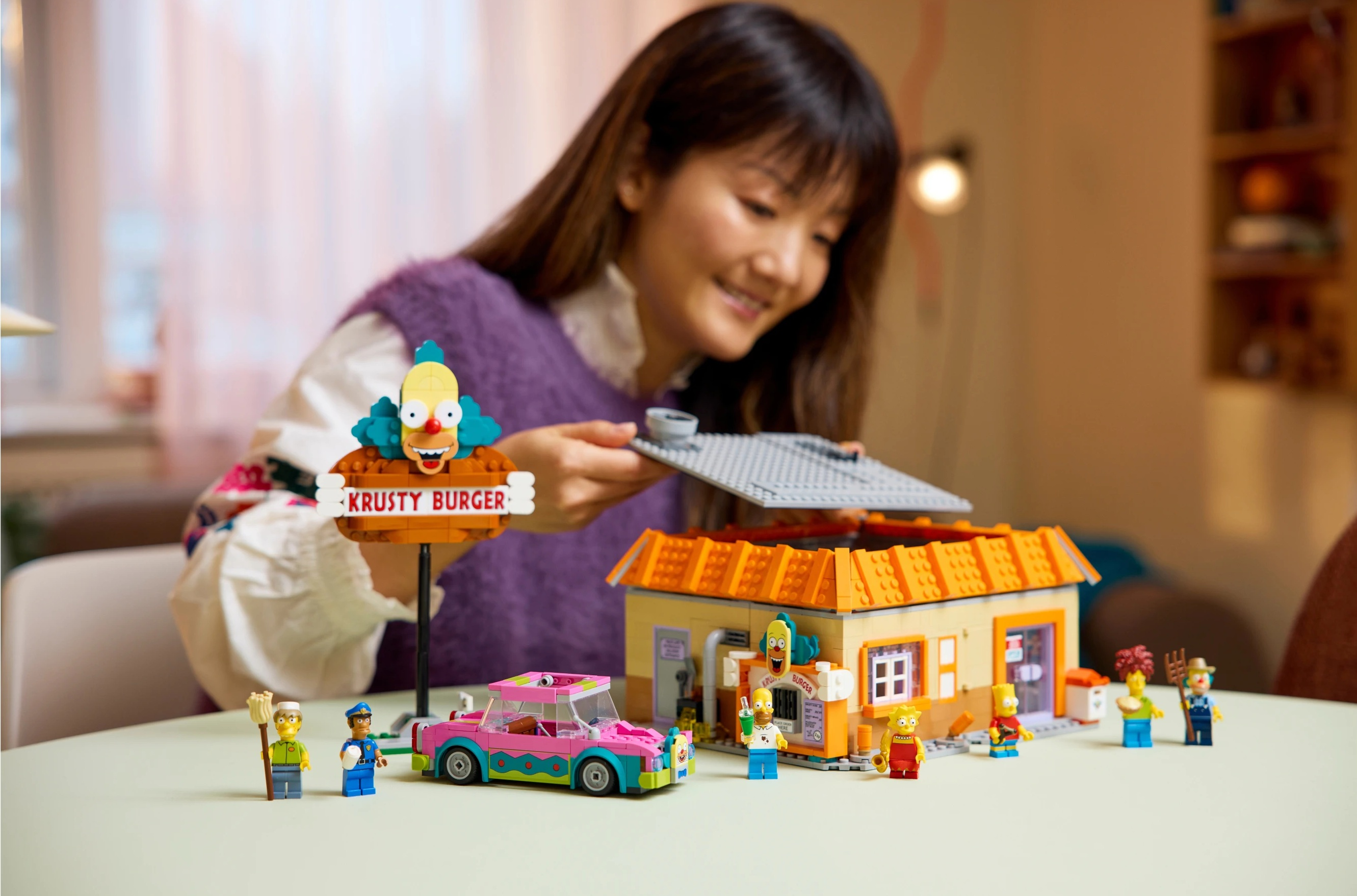 Kobieta buduje model Lego Krusty Burgera z Simpsonów z figurkami.
