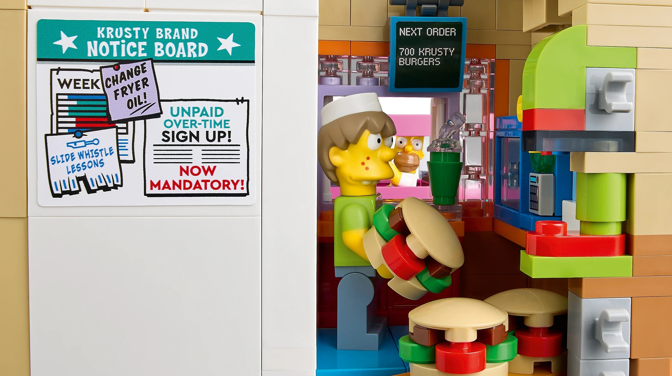 Mężczyzna trzyma burgera, za nim tablica "Następne zamówienie".