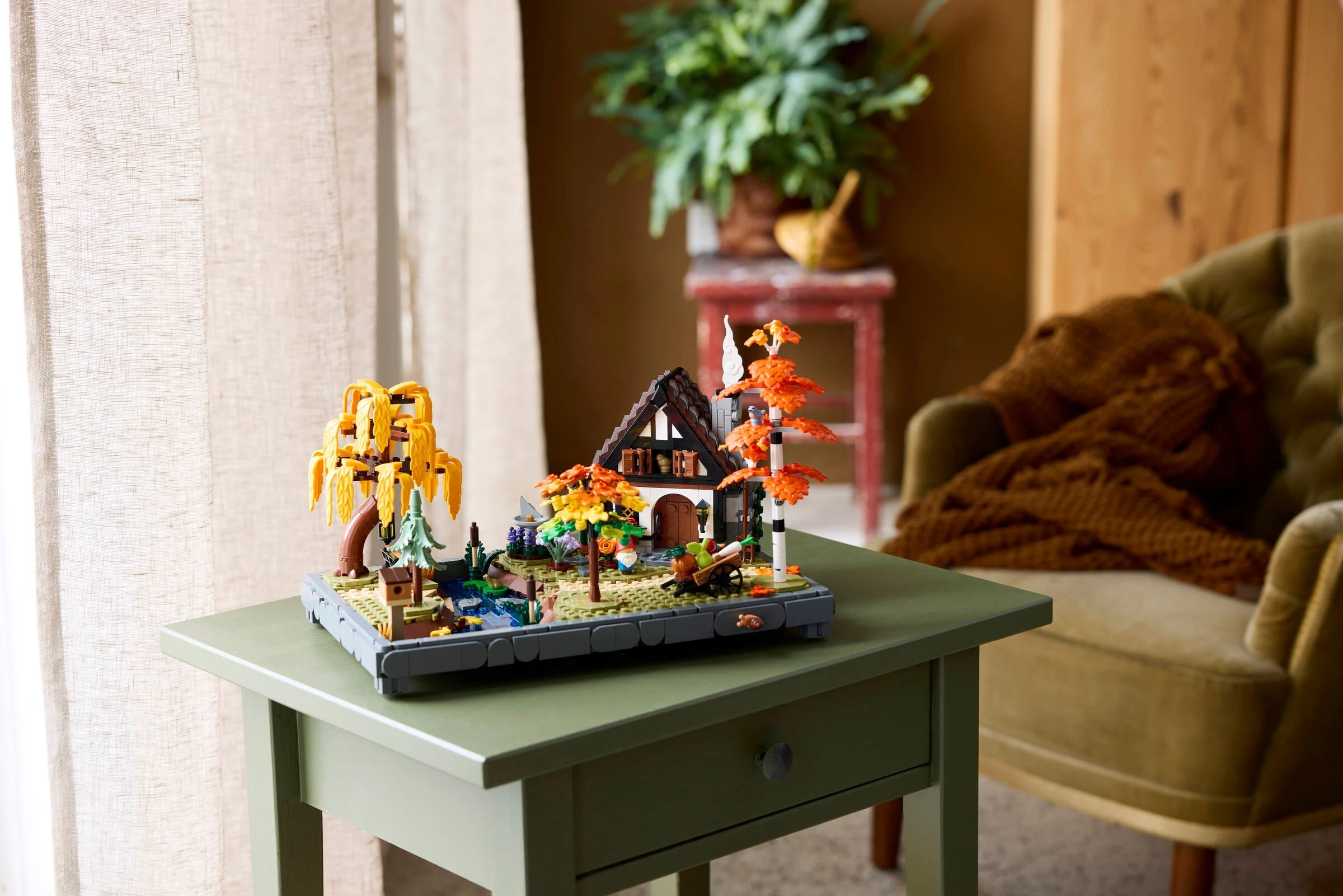 Model domu Lego z drzewami i stawem na stole.