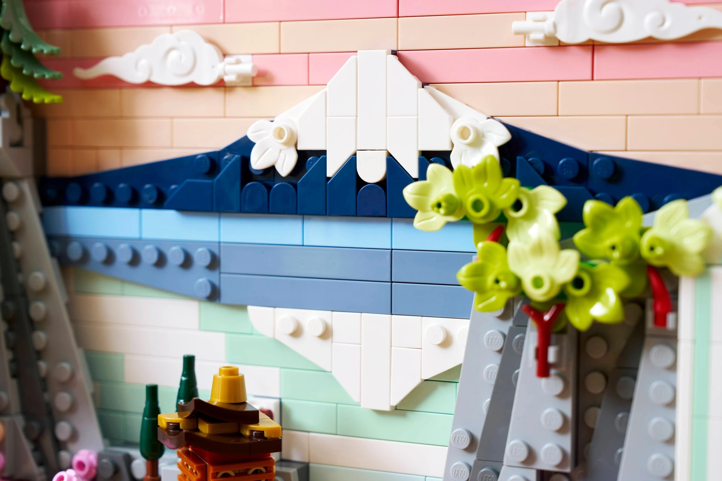 Model LEGO przedstawiający górę, chmury, drzewa i kwiaty.