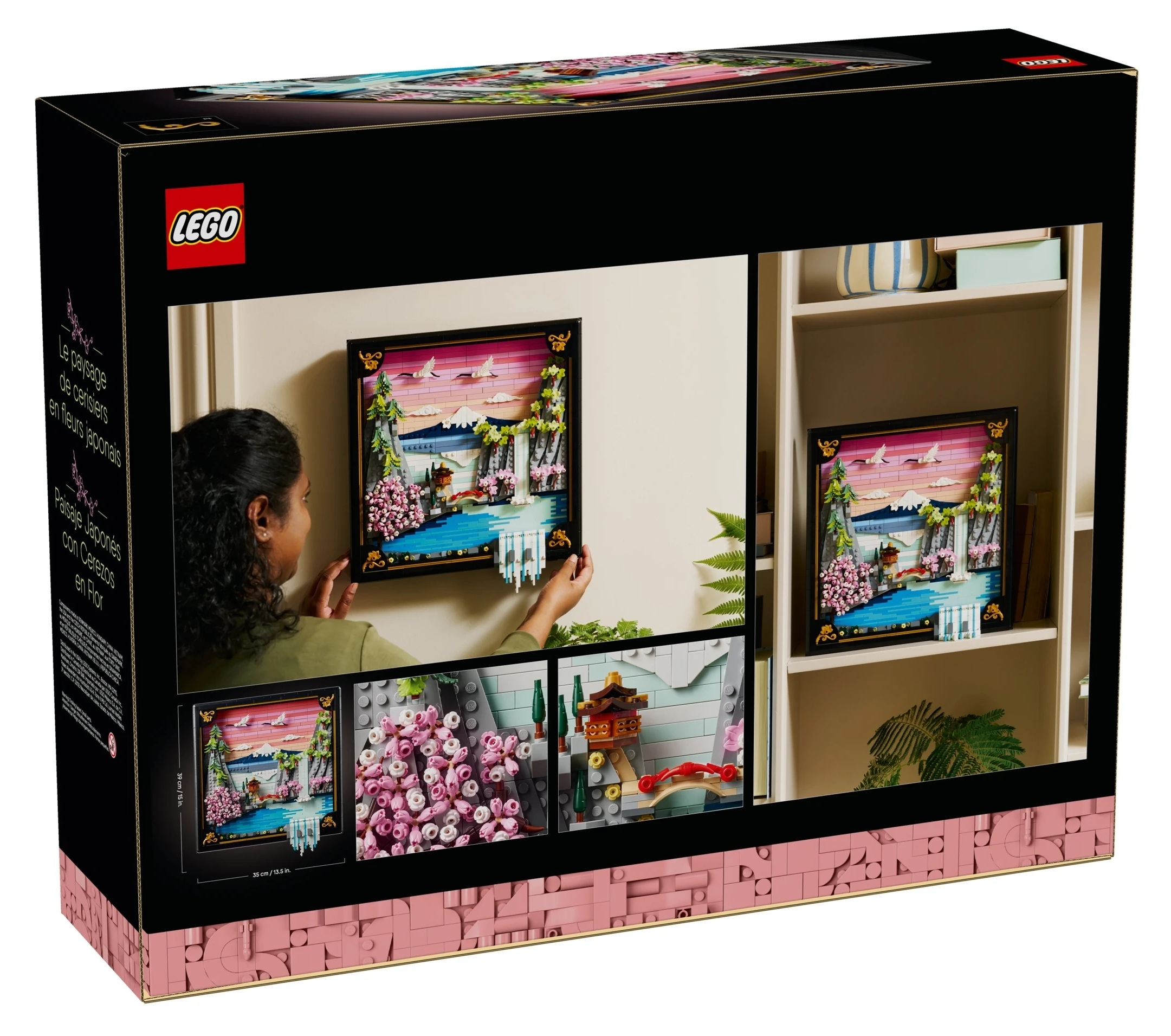 Pudełko Lego pokazuje kobietę wieszającą japoński obraz krajobrazu z kwitnącą wiśnią.