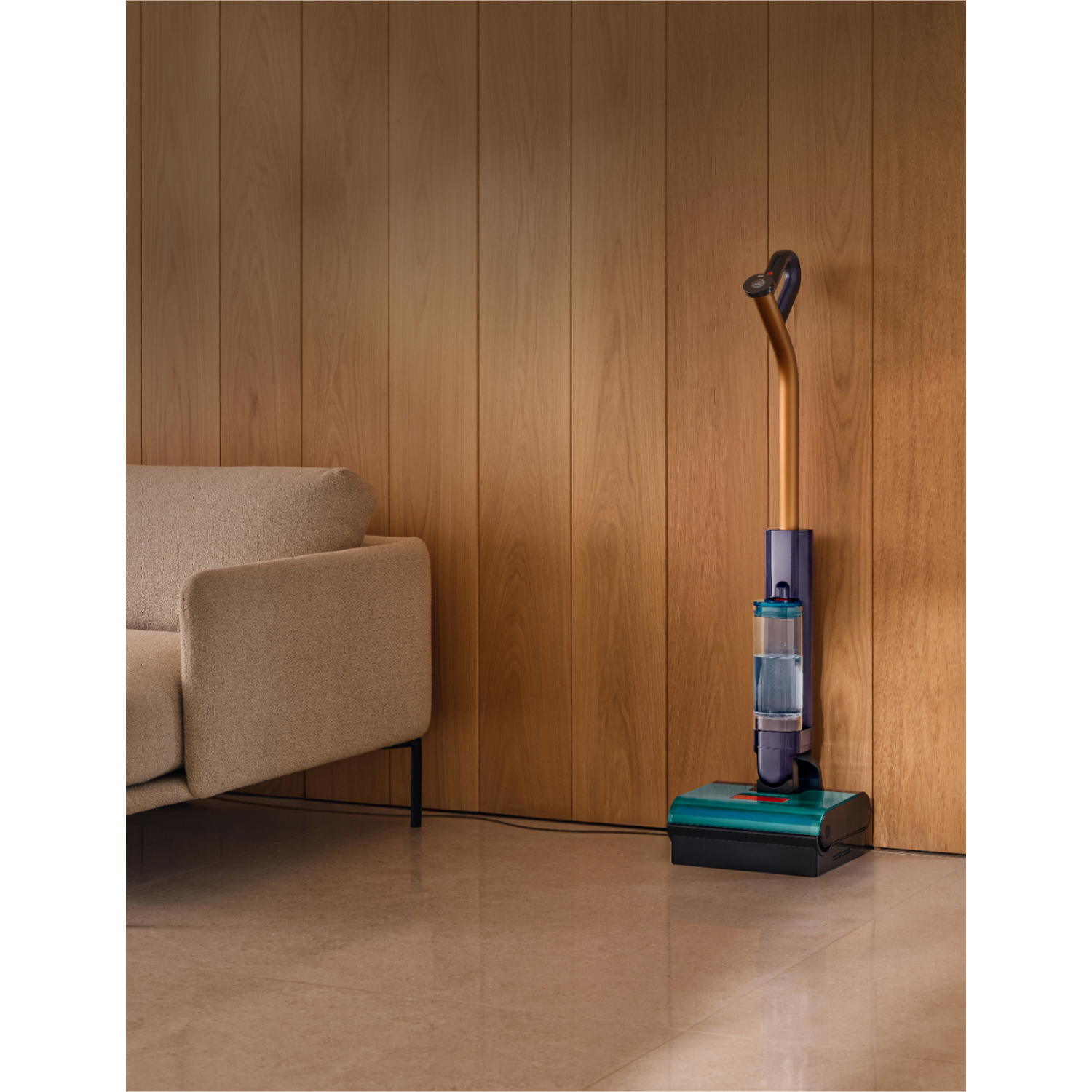A modern floor cleaner stands next to a sofa against a wood-paneled wall.