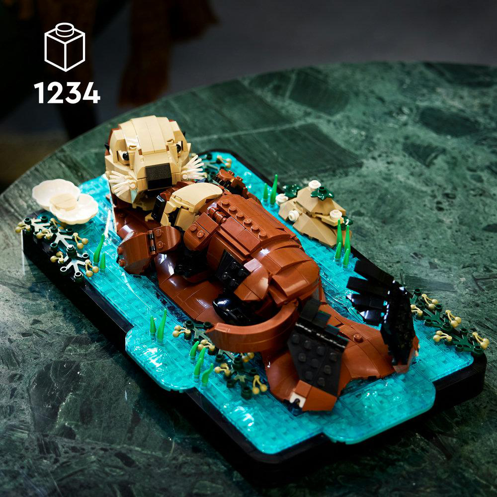 LEGO Otter-Modell schwimmt auf blauem Wasser mit grünen Pflanzen.