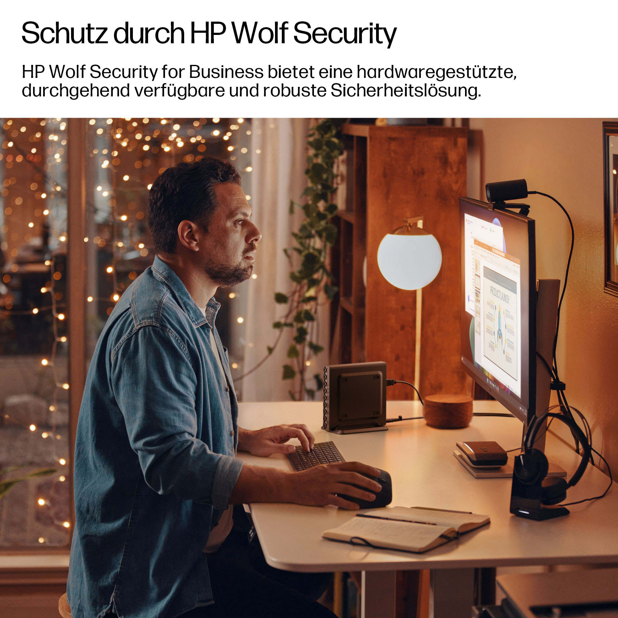 Mann sitzt am Schreibtisch und arbeitet am Computer, der Bildschirm zeigt eine Präsentation.