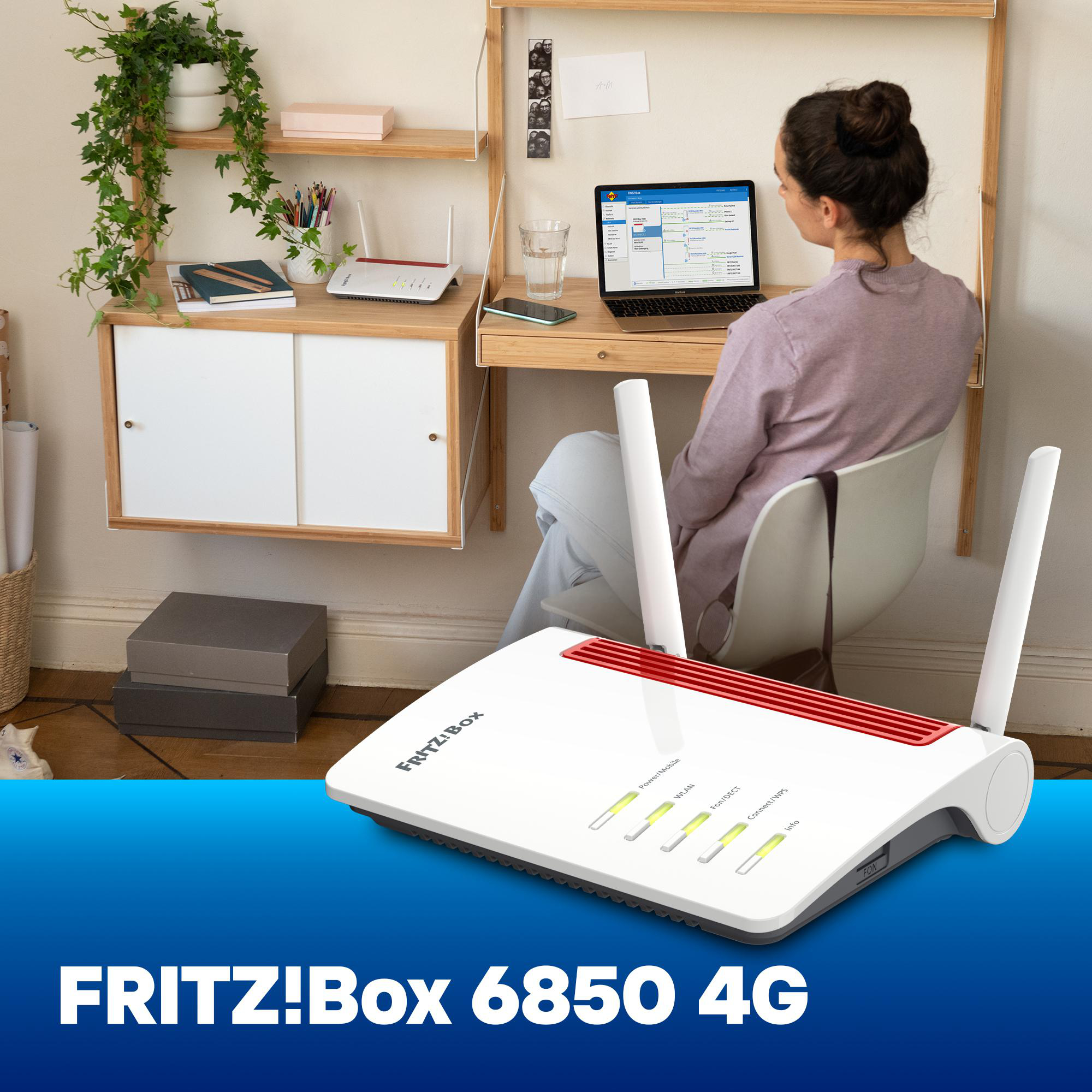 FRITZ!Box 6850 4G Router auf einem Schreibtisch mit einer Frau, die auf einem Laptop arbeitet.