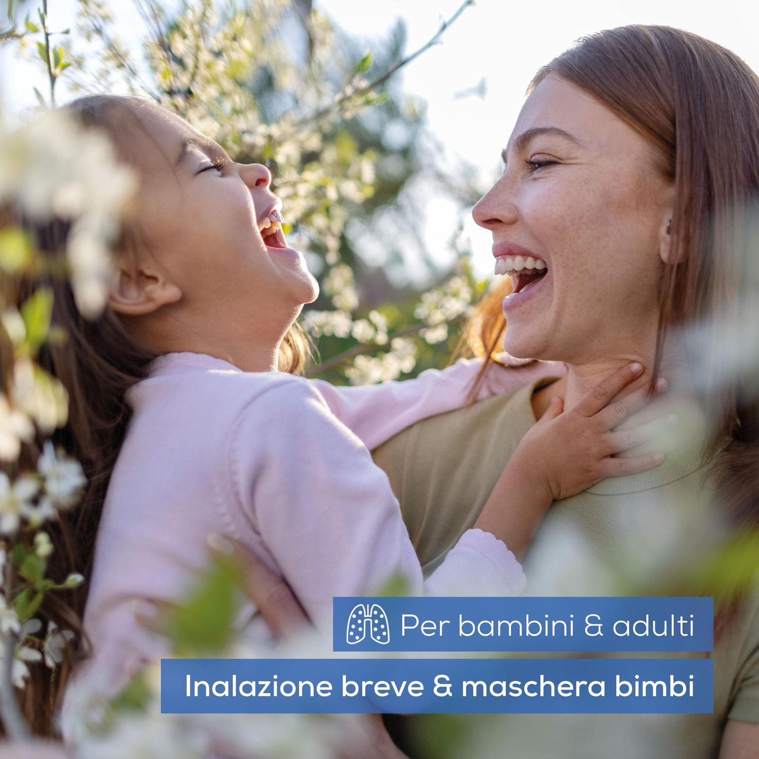 Donna e bambino ridono tra alberi in fiore.