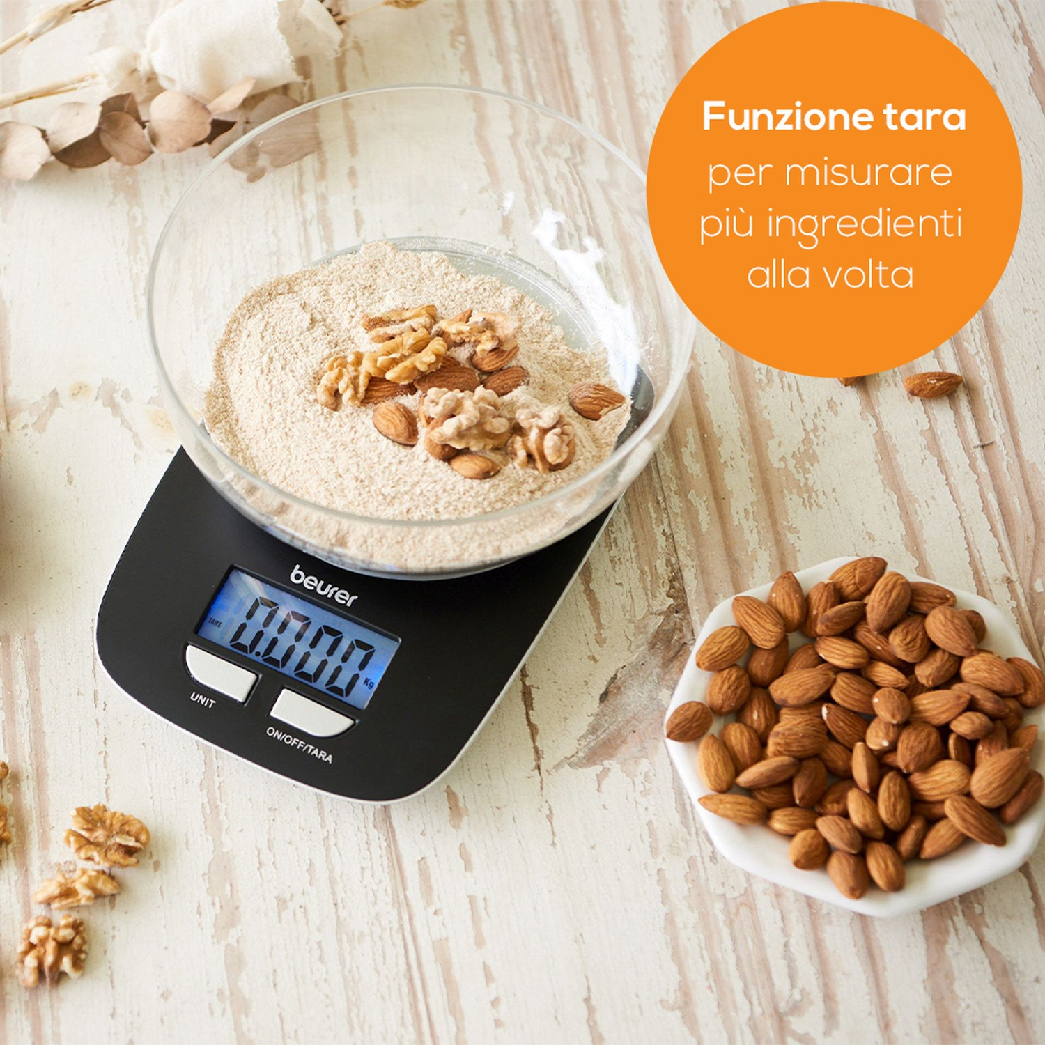 Una bilancia da cucina digitale con una ciotola piena di farina e noci.