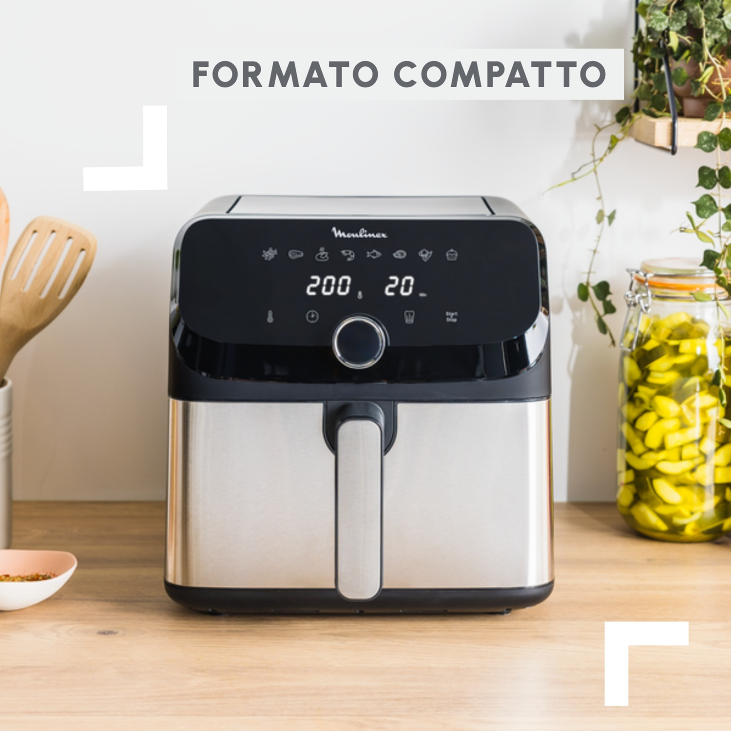 Elegante friggitrice ad aria argentata con display digitale, accanto a barattolo di sottaceti.