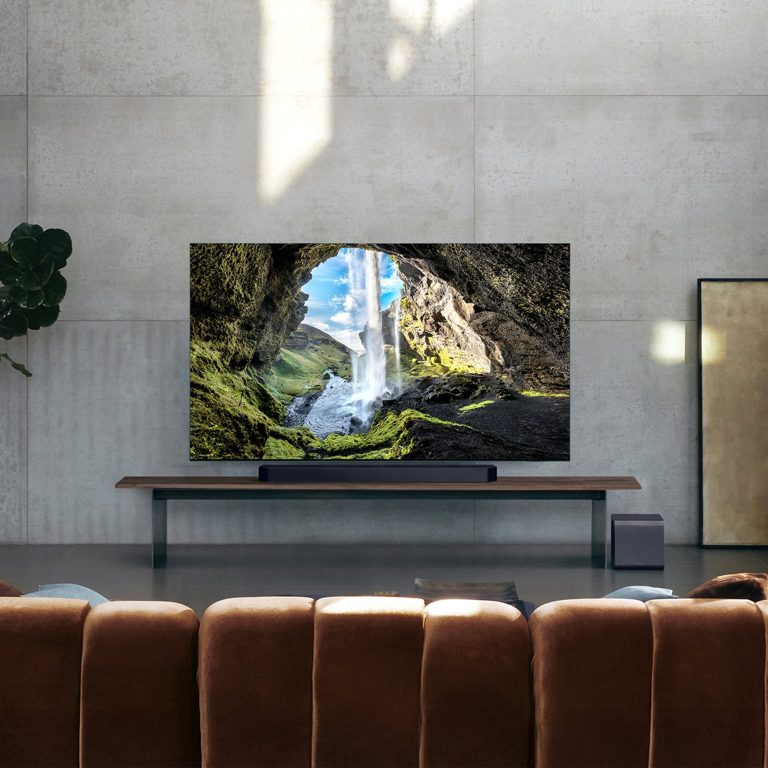 Un televisore mostra una cascata in una grotta, davanti a un soggiorno moderno.