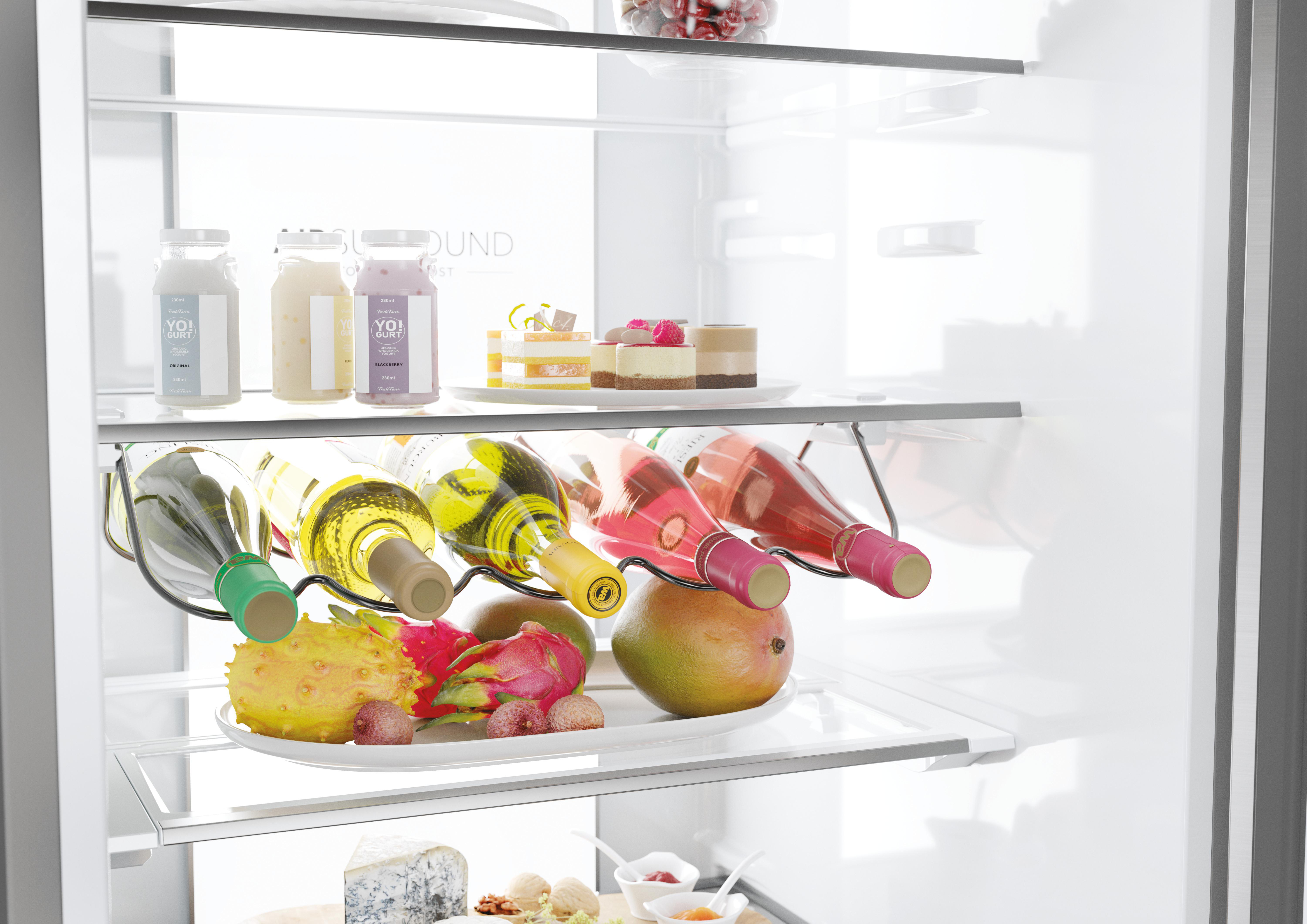 Kühlschrank mit Joghurtflaschen, Wein, Obst und Kuchen auf den Regalen.