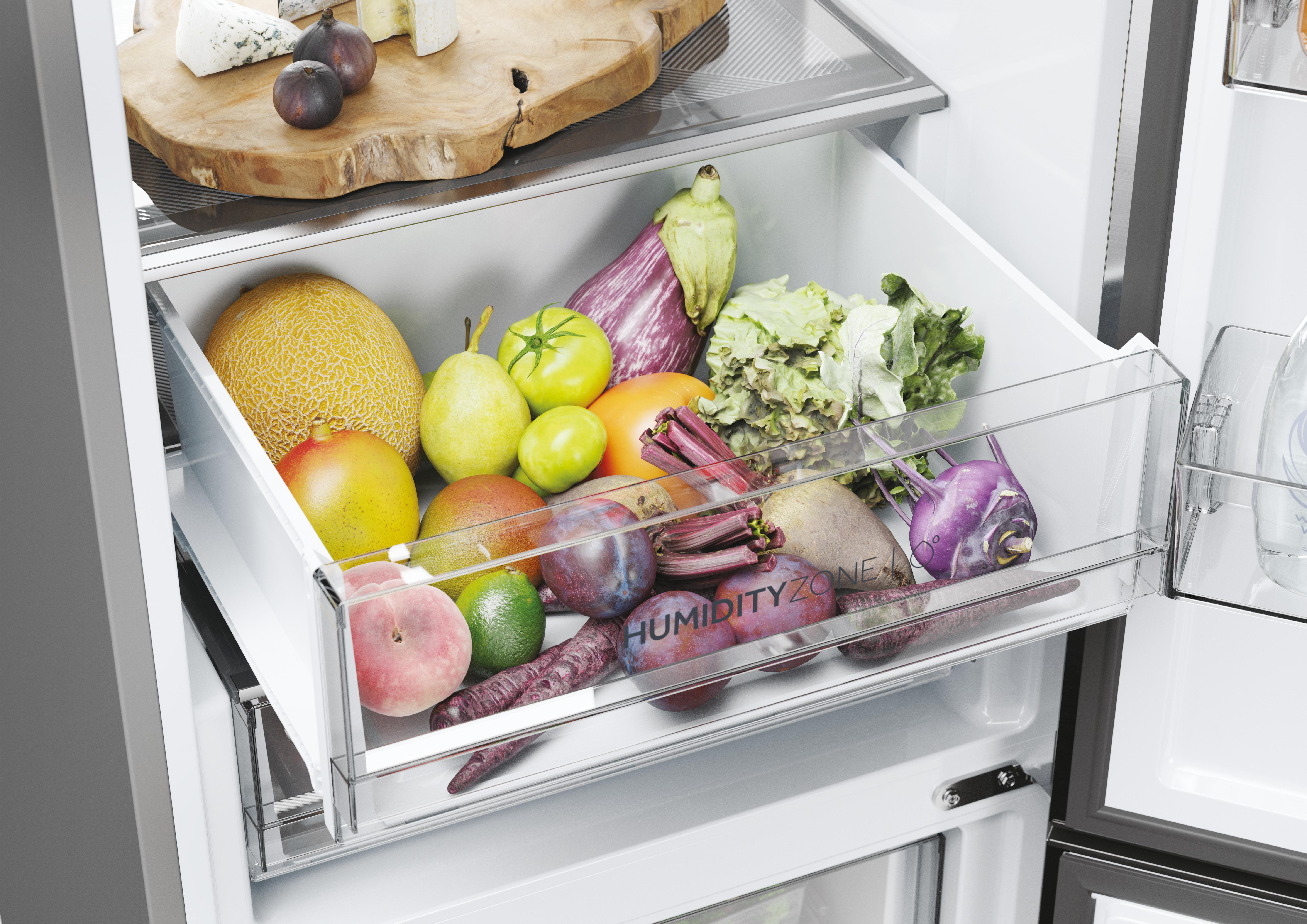 Ein Kühlschubfach voller Obst und Gemüse wie Melone, Birnen, Tomaten, Auberginen und Beeren.