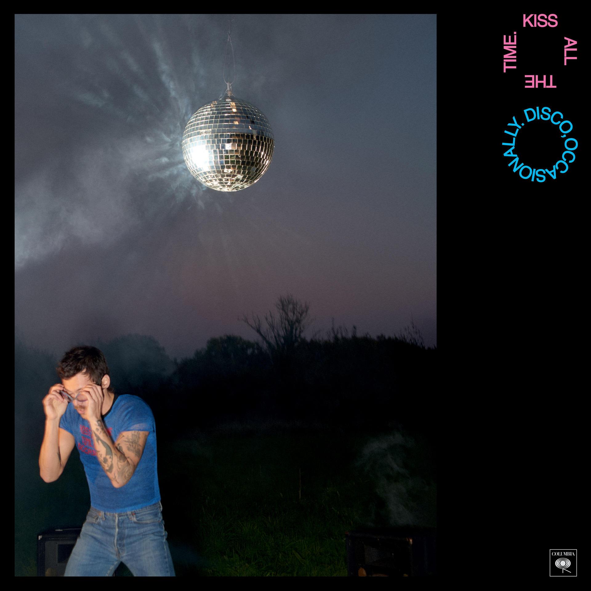 Ein Mann im blauen T-Shirt und Jeans tanzt unter einer Discokugel bei Nacht.