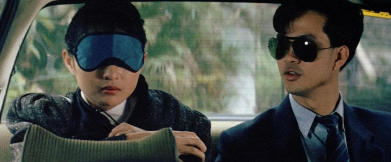 Mann mit Sonnenbrille und Frau mit Schlafmaske sitzen im Auto.