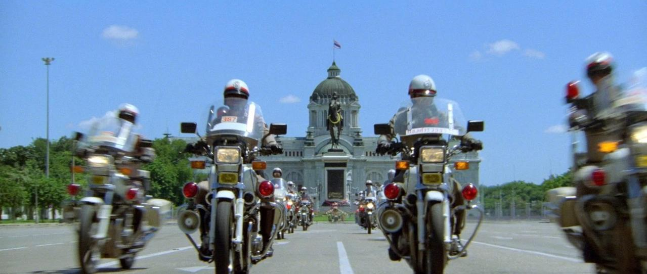 Motorradpolizisten fahren auf einer Straße vor einem großen Gebäude.