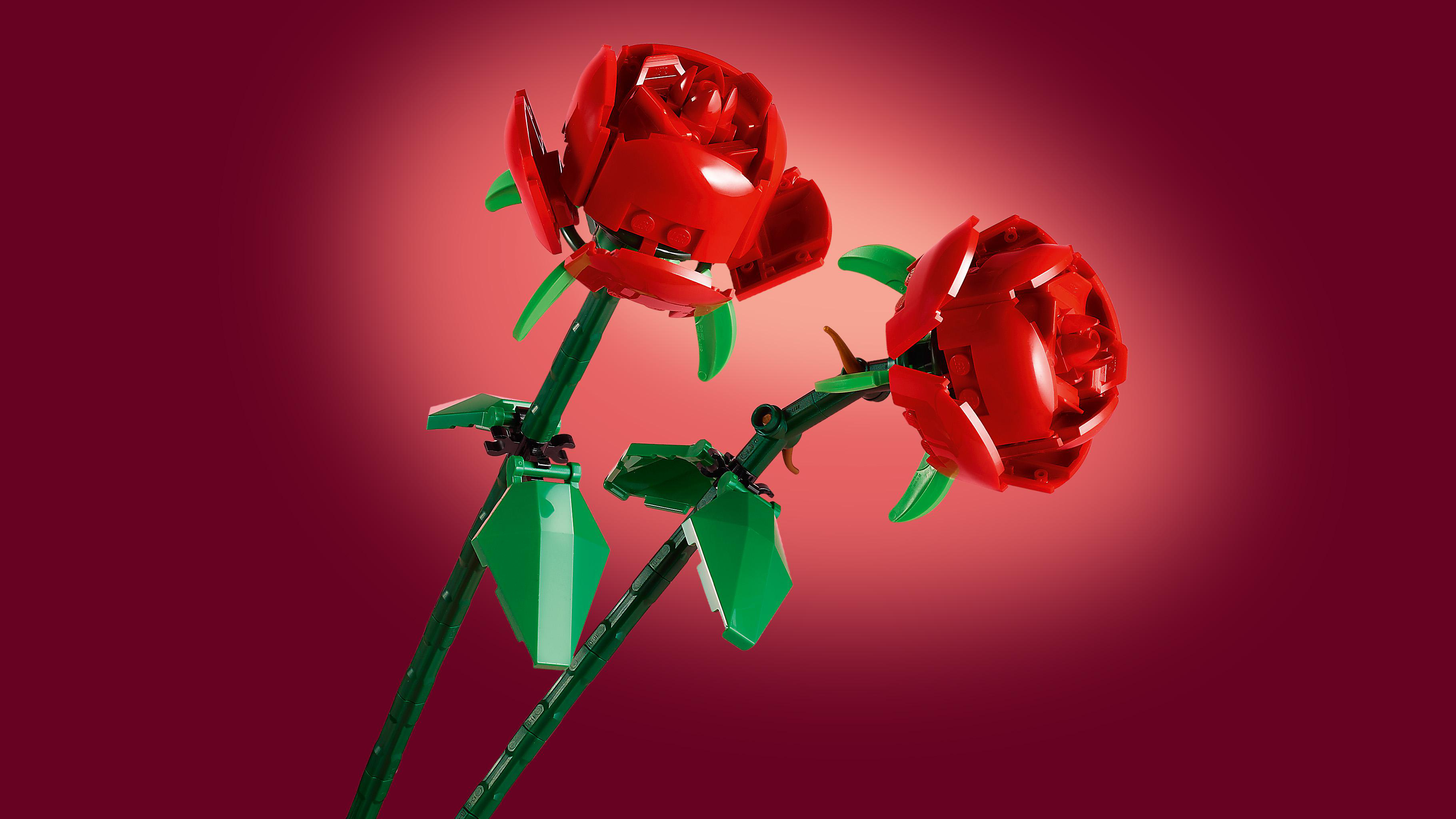Zwei rote Rosen aus Legosteinen mit grünen Stielen und Blättern.