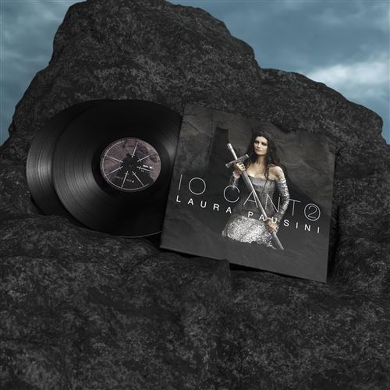 Vinylplaten en albumhoes met Laura Pausini tegen rotsen en wolken.