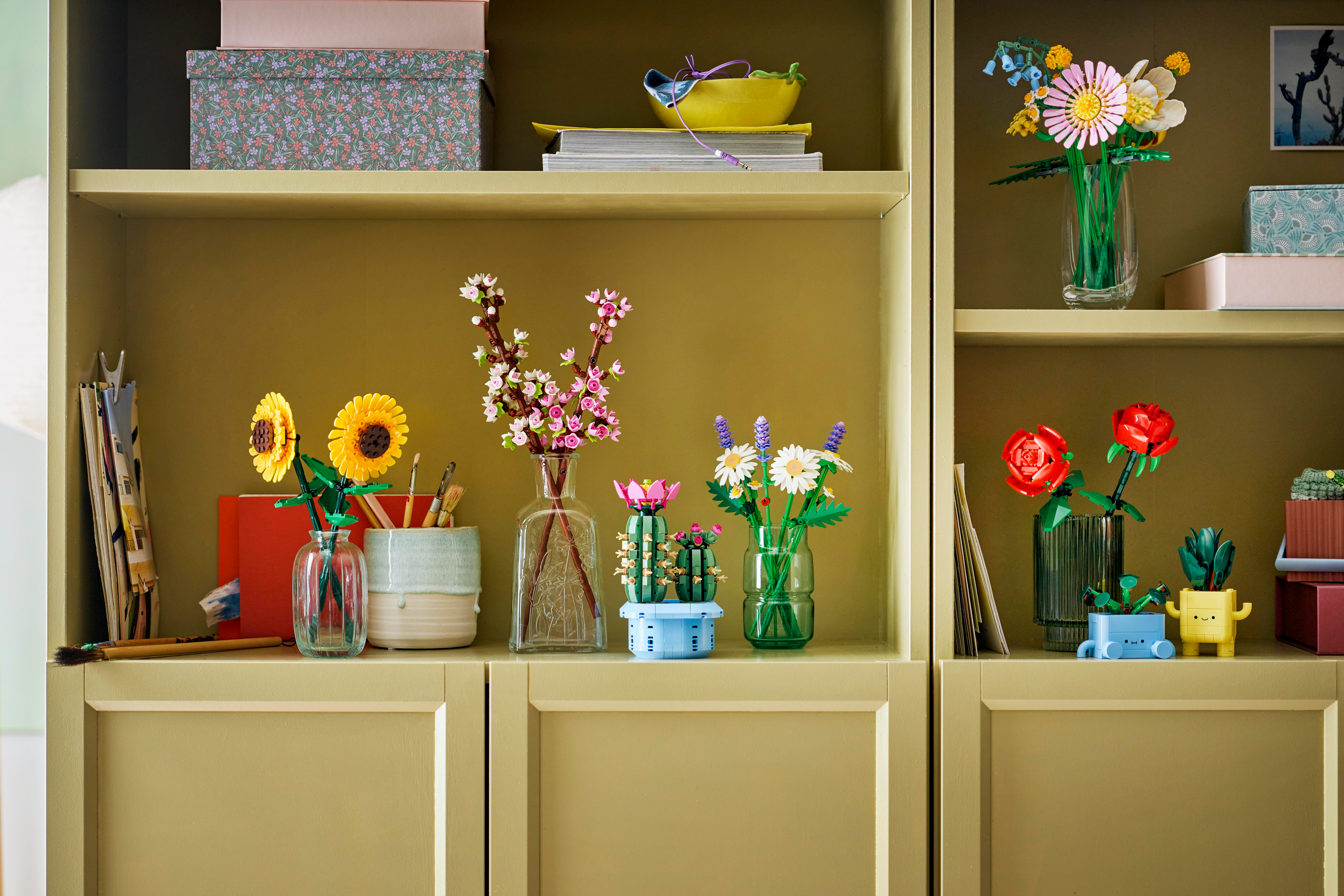 Ein Bücherregal mit Lego-Blumen und Pflanzen in Vasen.