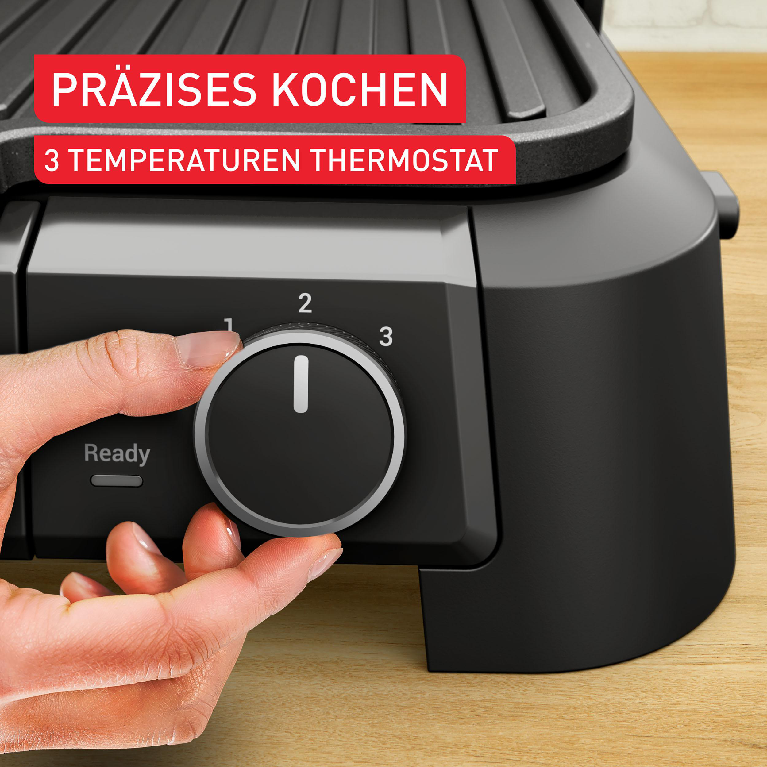 Eine Hand dreht den Temperaturregler einer schwarzen Grillplatte auf Stufe 1.