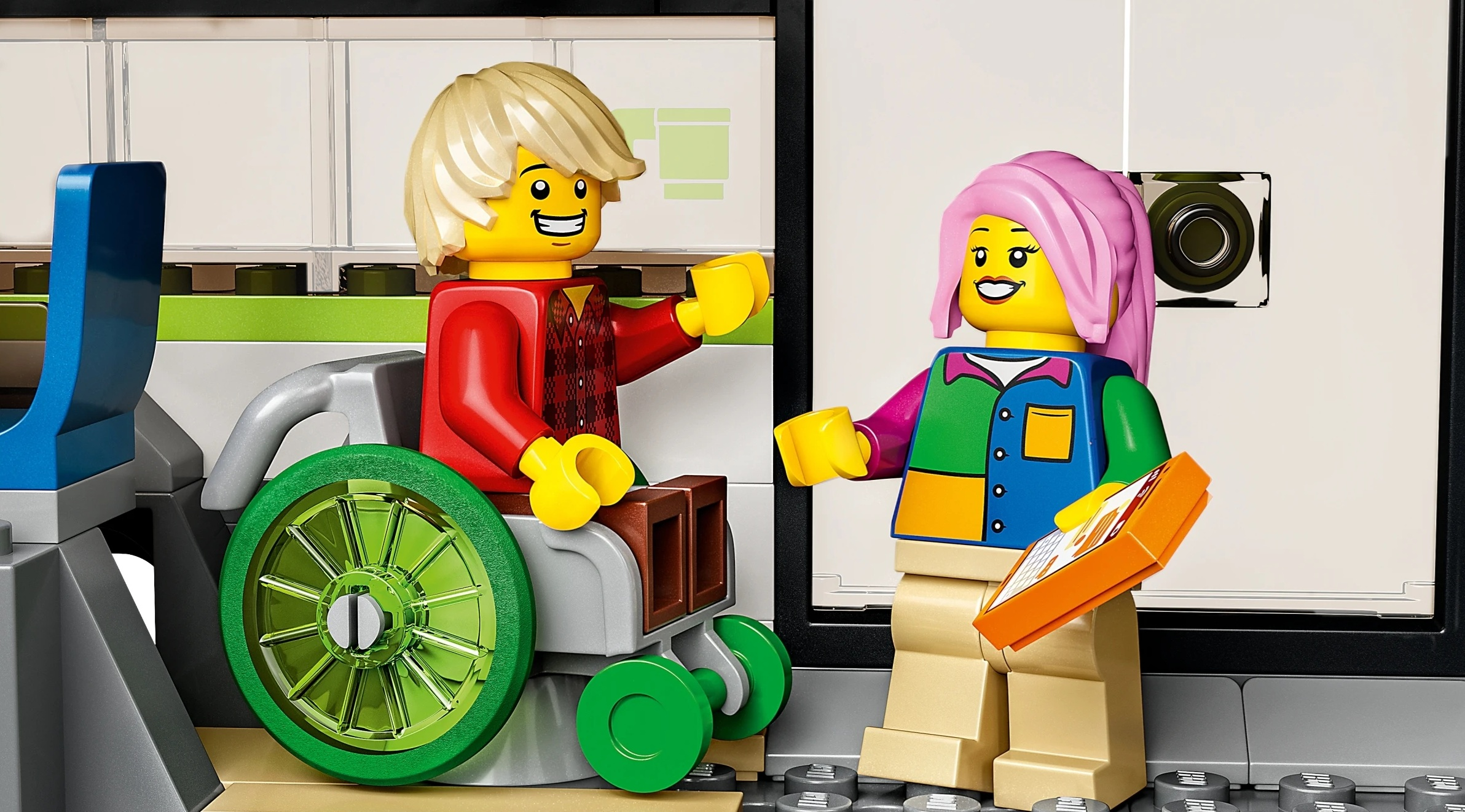 Mężczyzna na wózku inwalidzkim macha do kobiety z różowymi włosami trzymającej tablet.