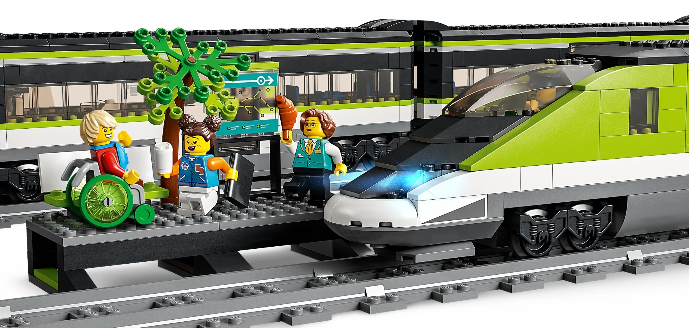 Figurki Lego na stacji z zielonym pociągiem. Jedna postać na wózku inwalidzkim.