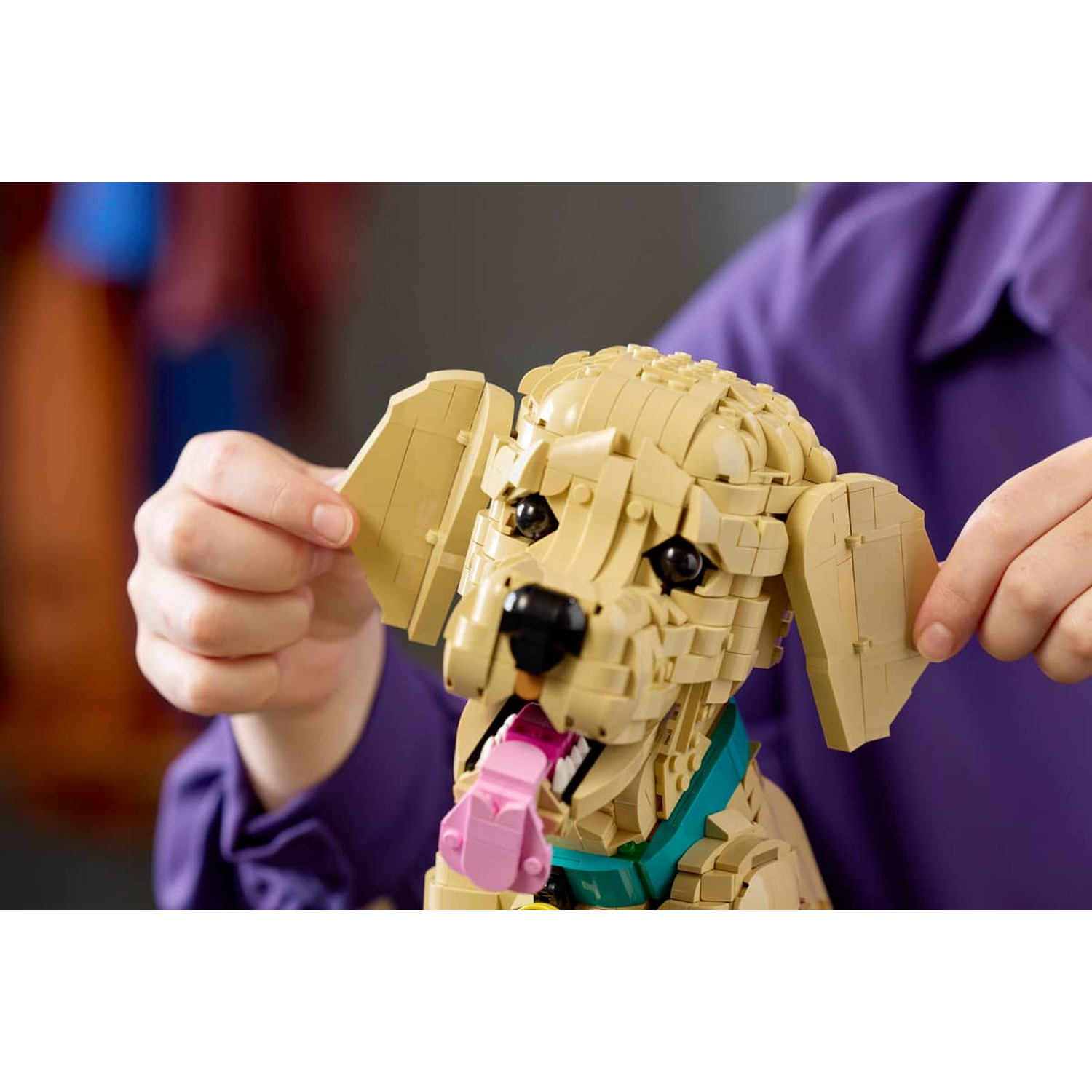 Een lichtbruine Lego hond met een roze tong en een turquoise halsband.