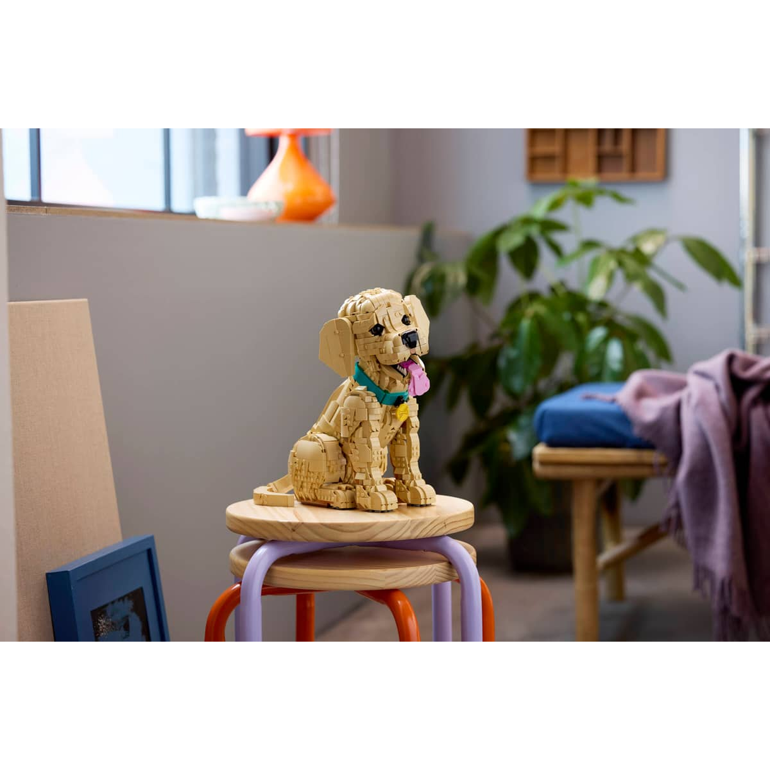 Een Lego-hond zit op een kruk voor een raam met een lamp.