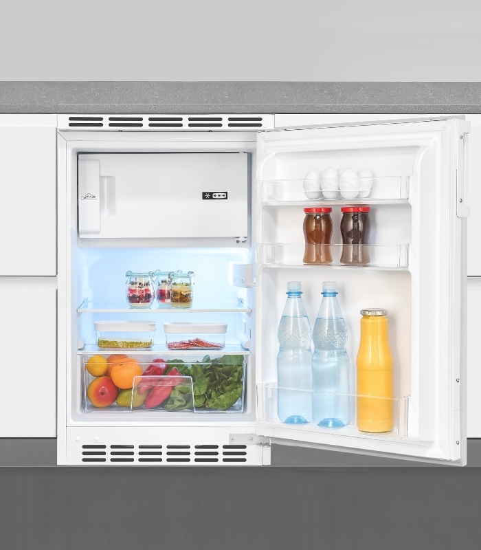 Ein offener Kühlschrank mit Lebensmitteln wie Eiern, Marmelade, Flaschen und Obst.