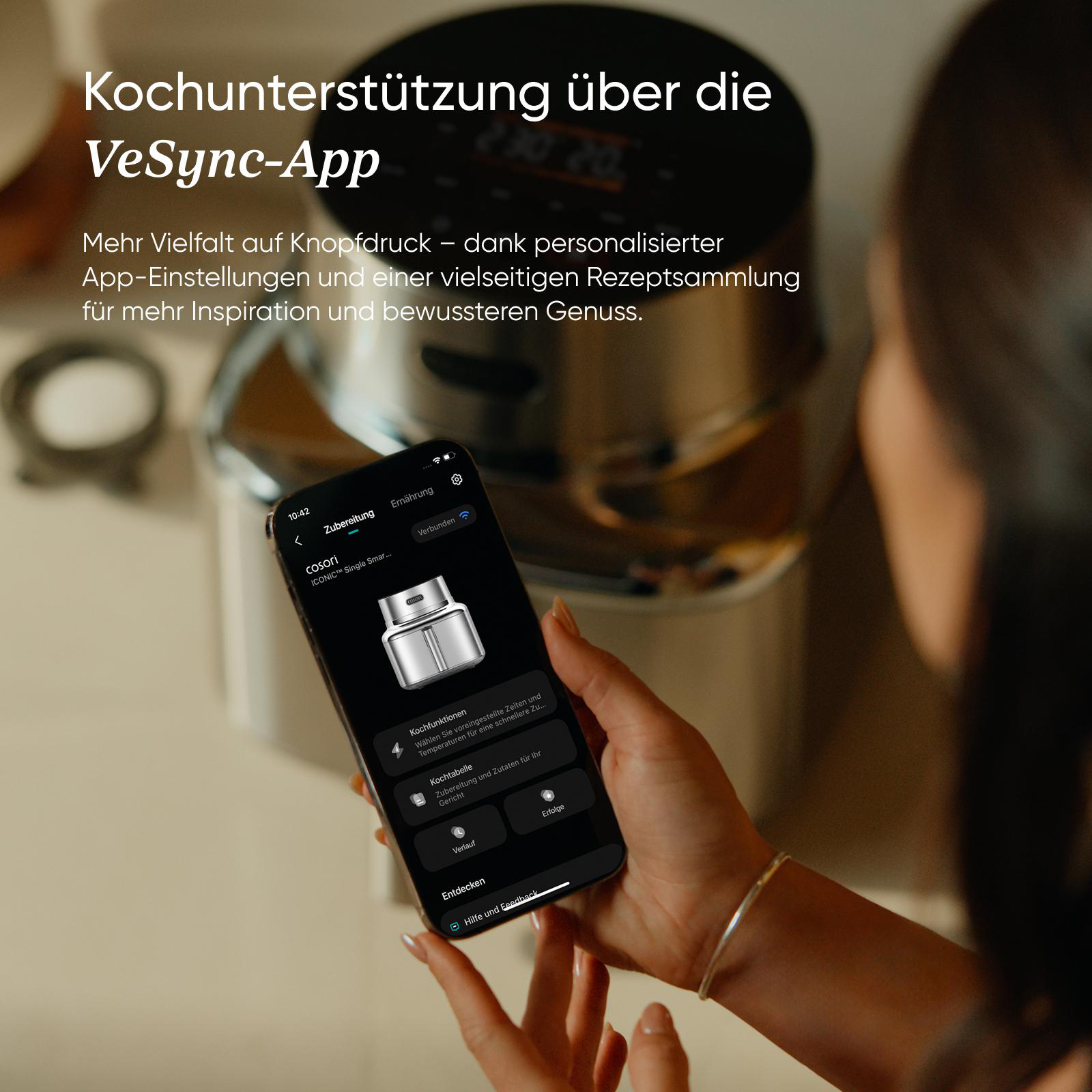 Eine Person hält ein Smartphone mit der VeSync-App, die Kochfunktionen zeigt.