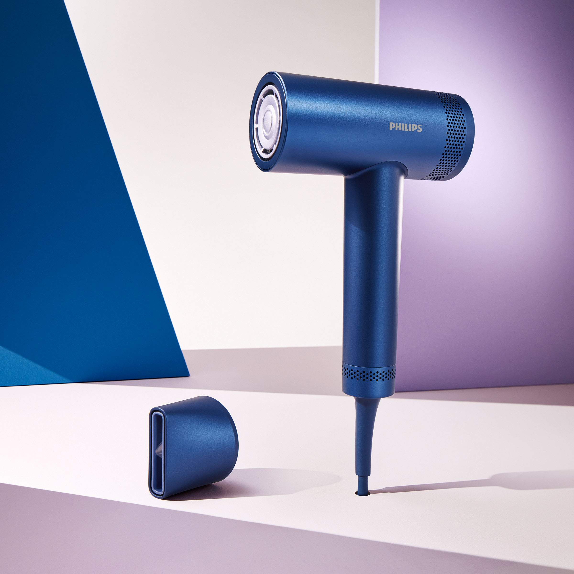 Niebieska suszarka Philips z osobną nasadką na jasnej powierzchni.
