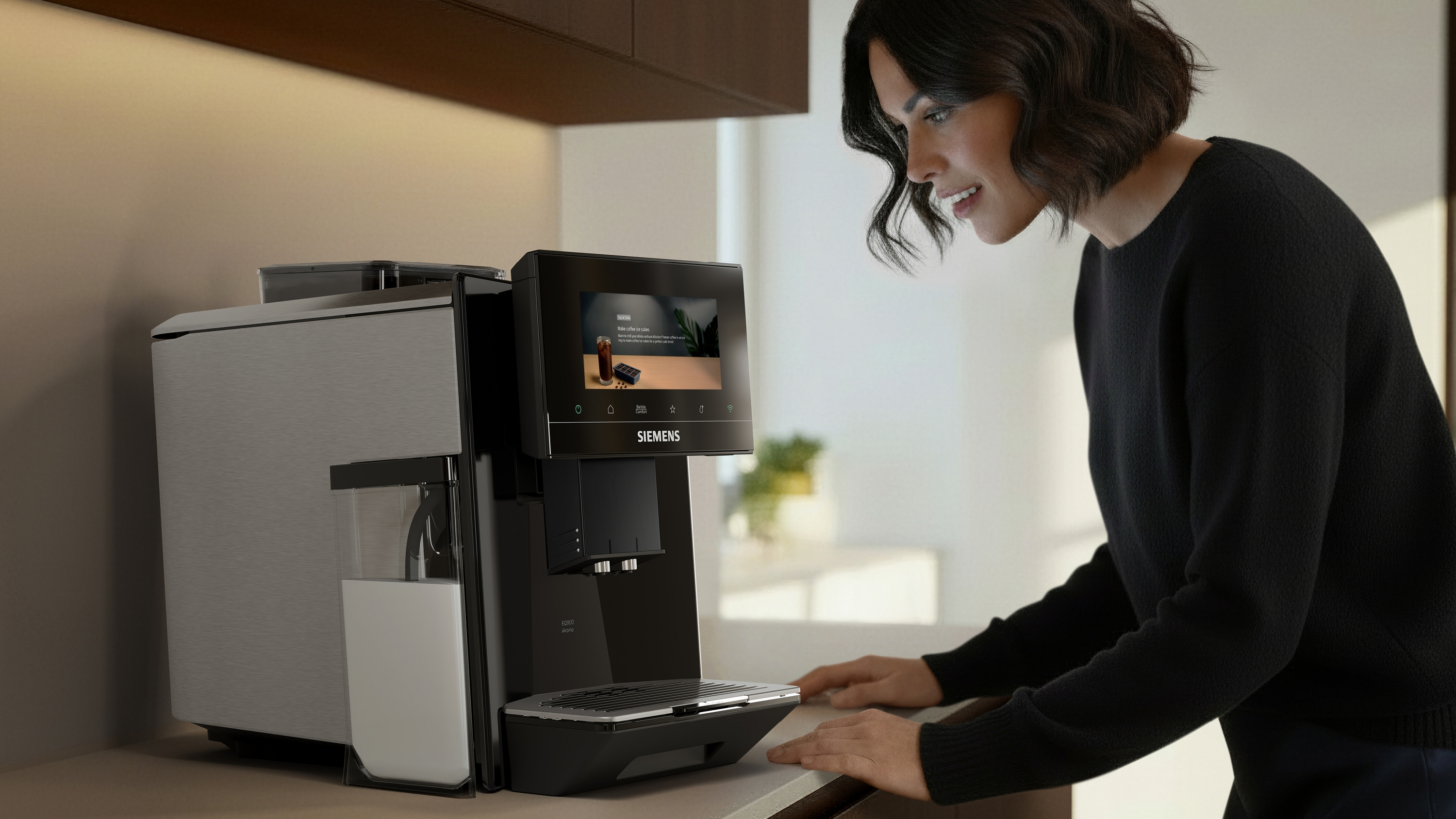 Une femme utilise une machine à café avec écran tactile.