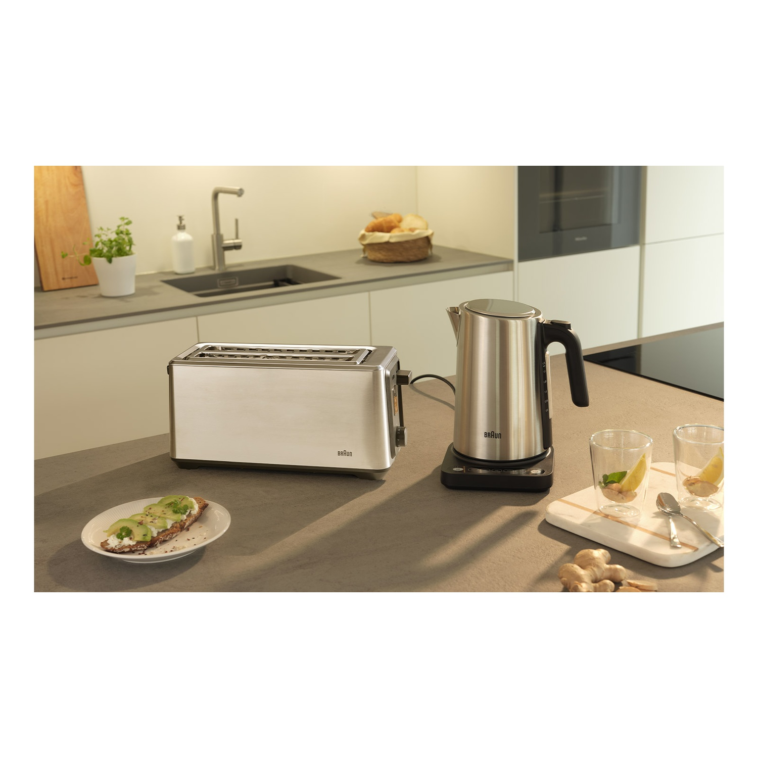Stainless steel toaster and kettle with avocado toast on a counter.