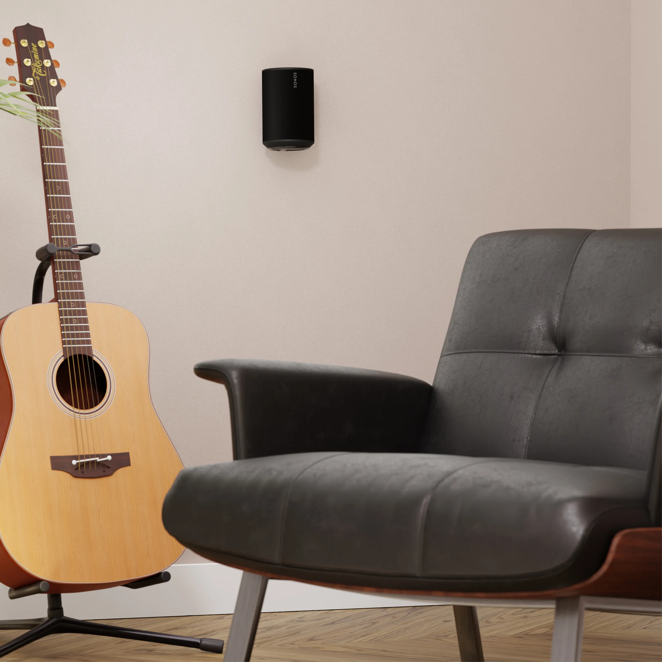 Eine Akustikgitarre steht neben einem schwarzen Ledersessel. Ein schwarzer Lautsprecher hängt an der Wand.