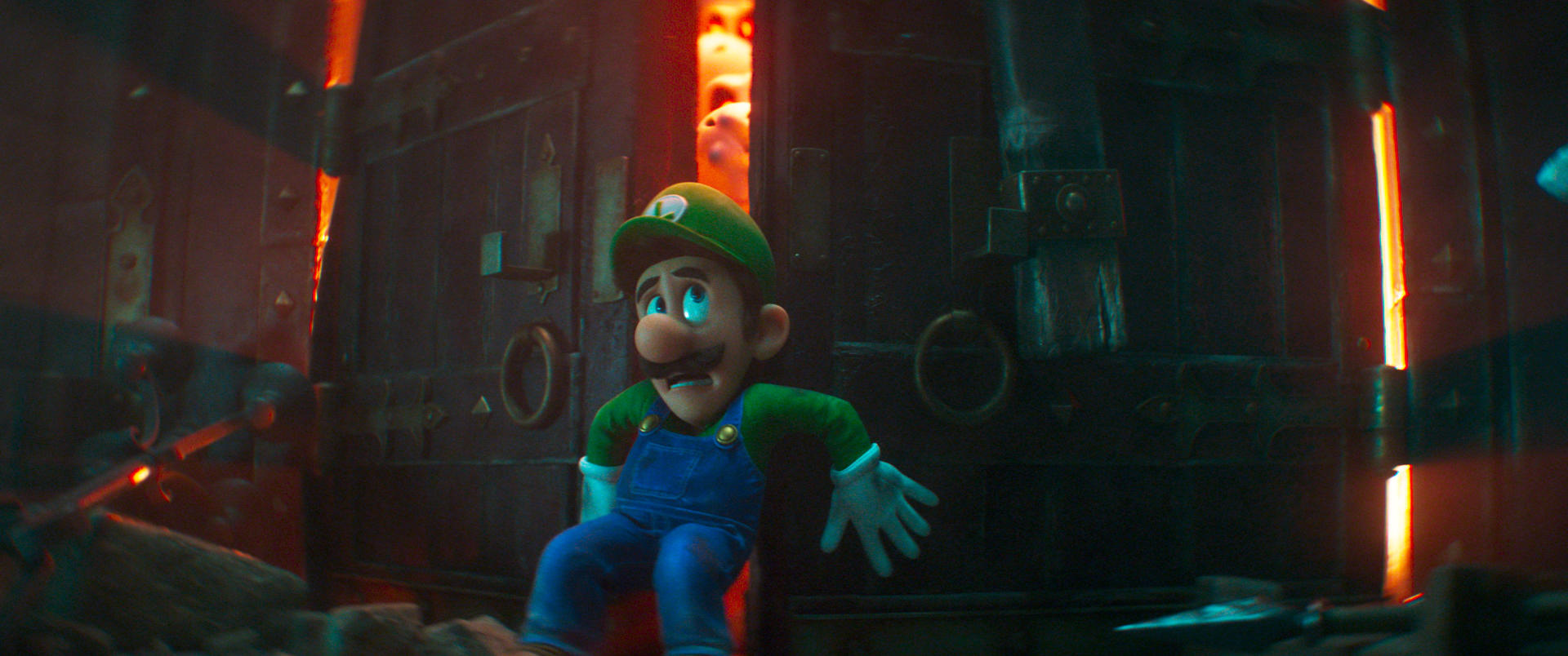 Luigi in blauer Latzhose und grünen Ärmeln blickt ängstlich in den Hintergrund.