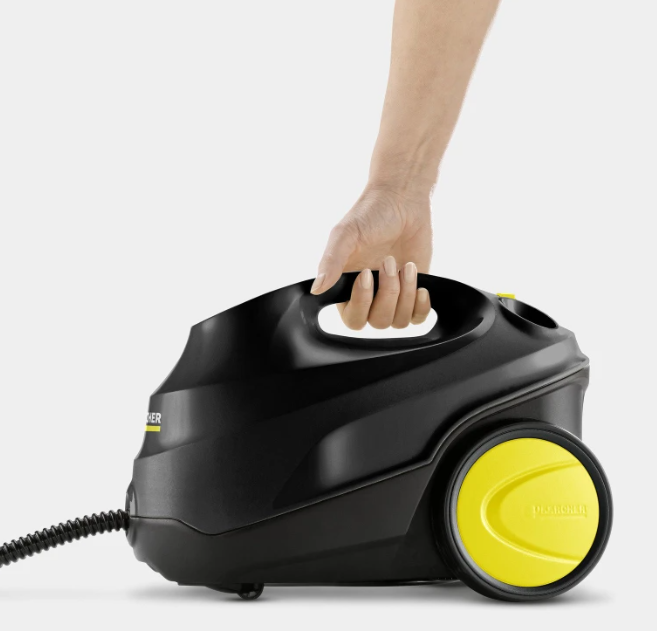 Ręka podnosi czarny odkurzacz parowy z żółtymi akcentami.