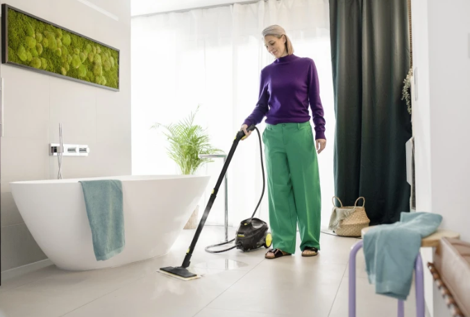 Kobieta czyści podłogę parownicą w nowoczesnej łazience.