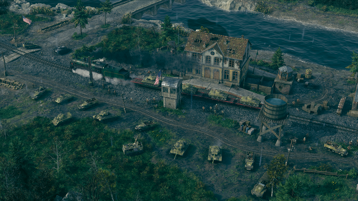 Un tren verde con tanques en vagones planos pasa junto a un edificio.