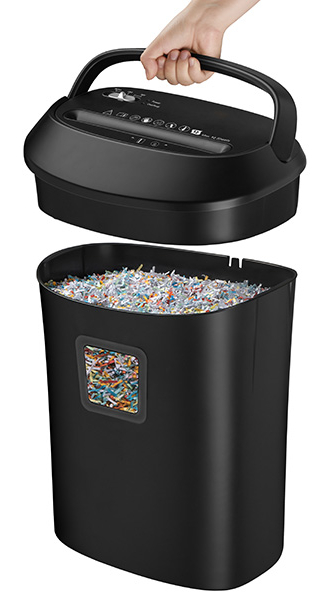 Dłoń unosi czarną niszczarkę do papieru nad pojemnikiem wypełnionym kolorowym, pociętym papierem.