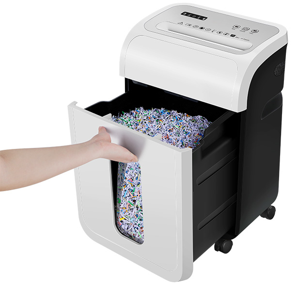 Ręka wyciąga szufladę pełną posiekanego papieru z niszczarki do dokumentów.