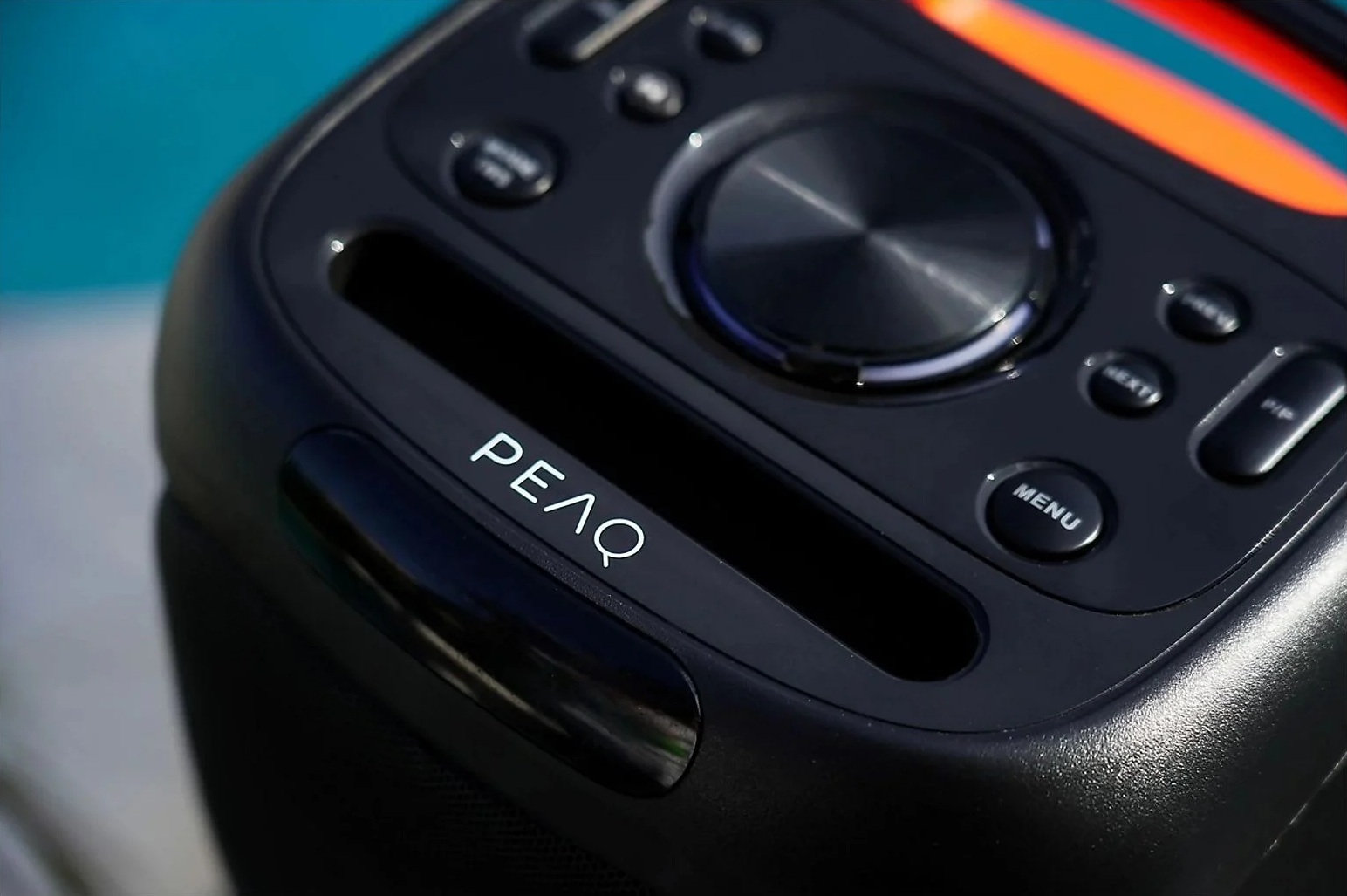 Czarny głośnik z elementami sterującymi, oświetleniem i logo PEΛQ.