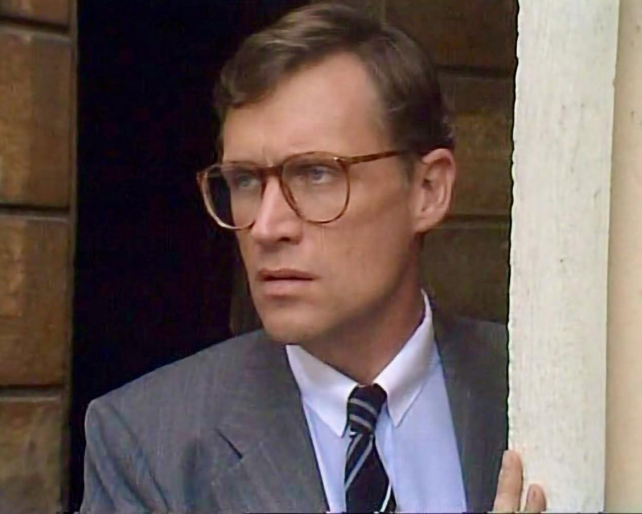 Ein Mann mit Brille in Anzug und Krawatte blickt nach links.