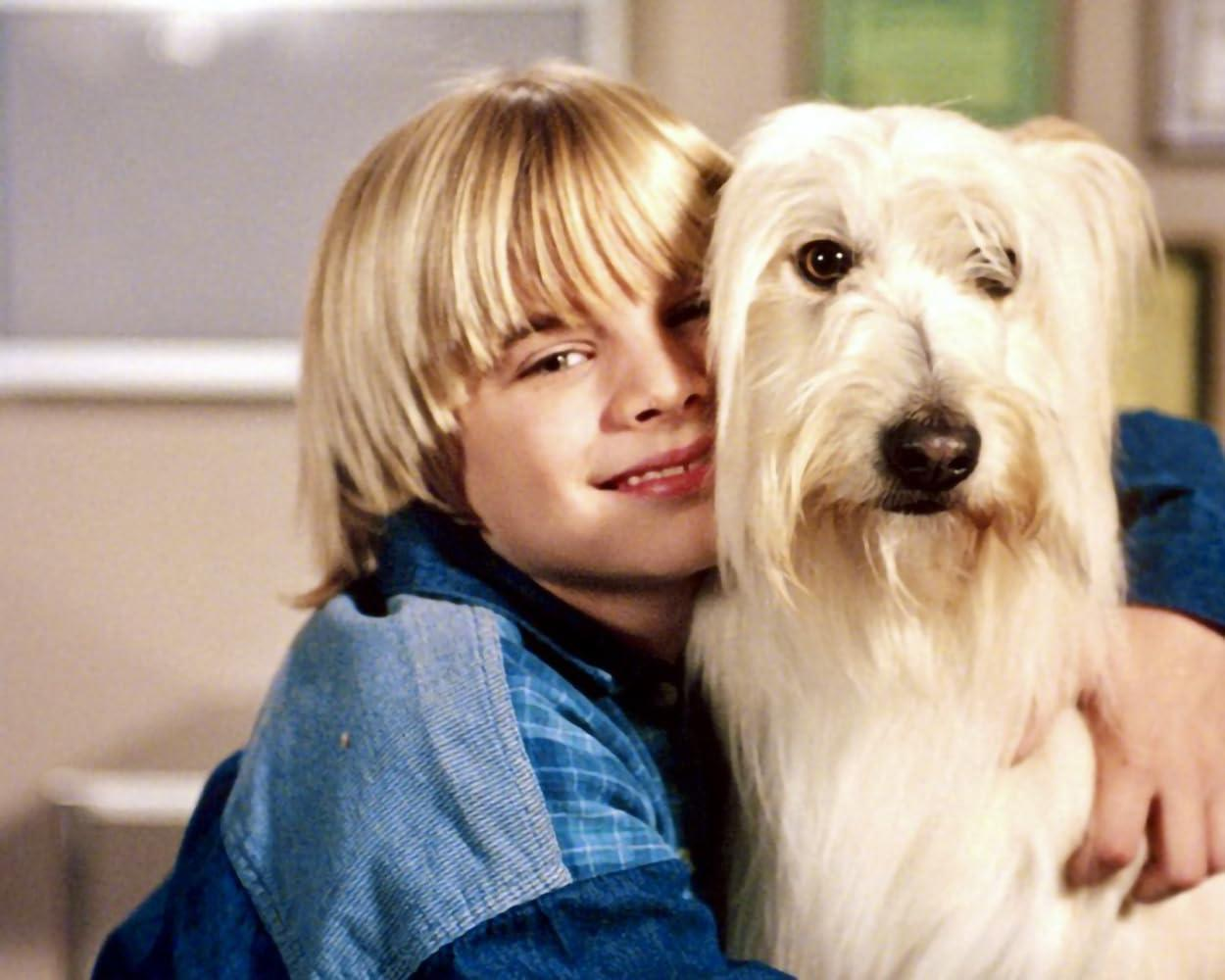 Ein Junge mit blonden Haaren umarmt einen weißen Hund.