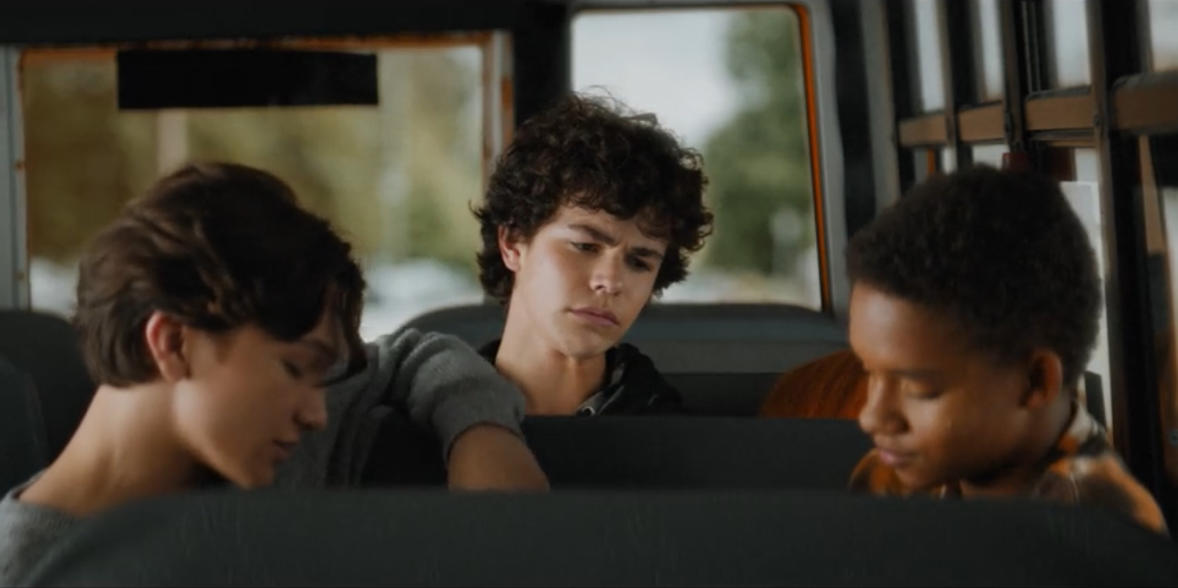 Drei Jungen sitzen in einem Bus. Einer starrt nachdenklich aus dem Fenster.