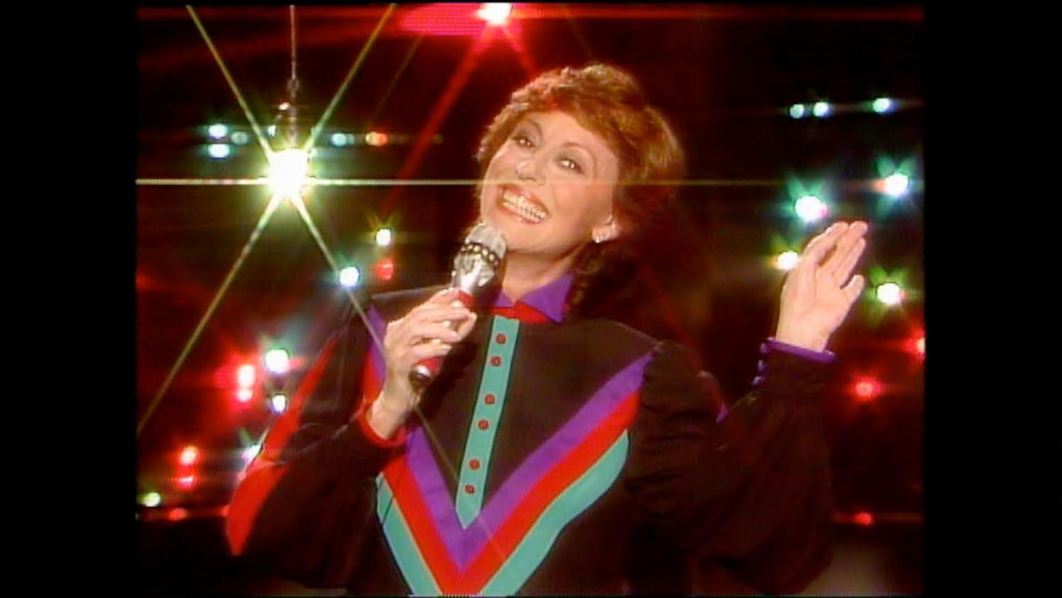 Eine Frau mit Mikrofon singt auf einer Bühne mit Lichtern.